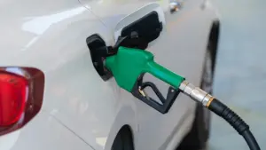 Degvielas uzpildes pistole ievietota baltas automašīnas degvielas tvertnē degvielas uzpildes stacijā