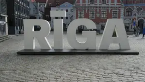 Liels, balts uzraksts RĪGA uz bruģēta laukuma Rīgas vēsturiskajā centrā dienā.