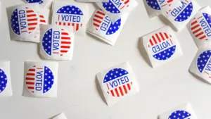 Vairākas "I voted" uzlīmes izkārtotas uz baltas virsmas, simbolizējot pilsonisko līdzdalību vēlēšanās.