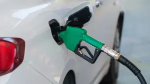 Degvielas uzpildes pistole ievietota baltas automašīnas degvielas tvertnes atverē degvielas uzpildes stacijā.