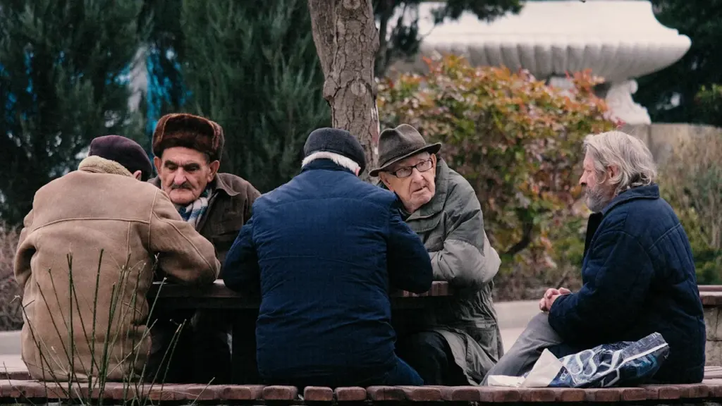Vīrieši vidējā un vecākā vecumā sēž pie galda, atgādinot par senām draudzības saitēm un sarunām.