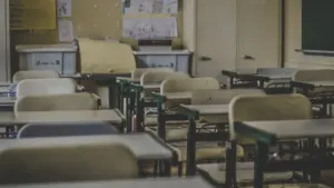 Tukša skolas klase ar soliem un mācību materiāliem pie sienas.