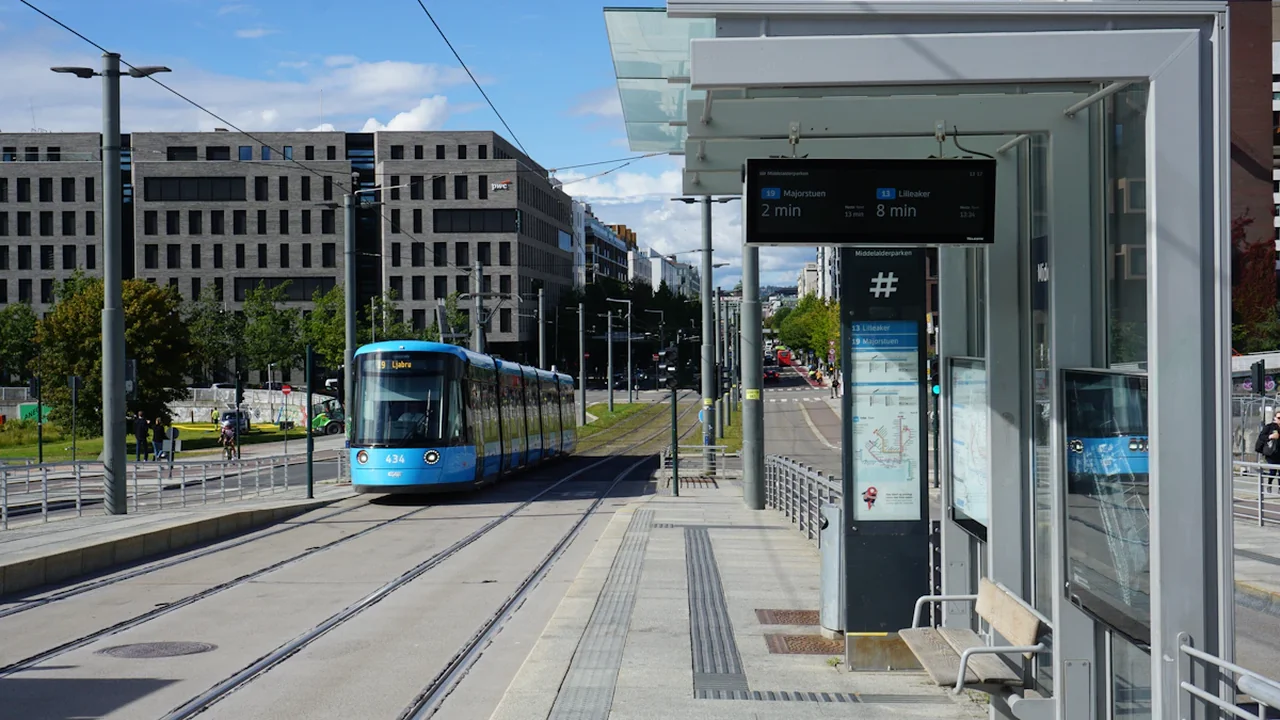 Mūsdienīga tramvaja pietura ar elektronisko tablo un sliedēm pilsētas centrā.